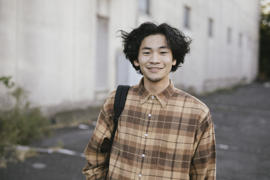 Smiling Asian man with long hair looking at camera.
