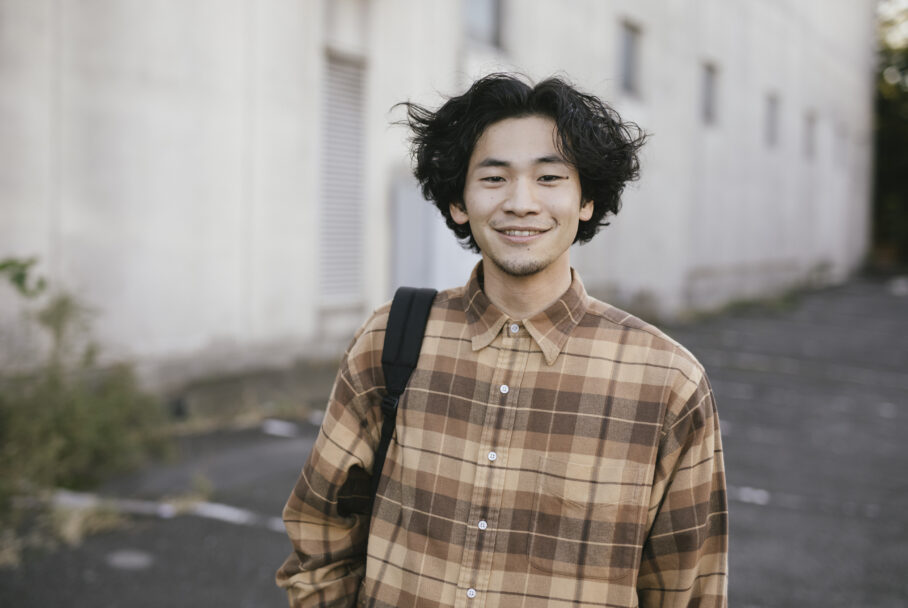 Male student with long hair wearing a backpack looking at camera.
